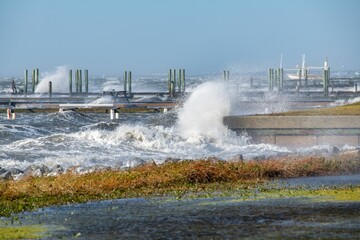 Waves splashing on stone piers on the beach in the winter with blue sky