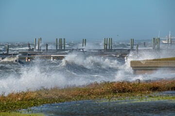 Landscape of Rough waves splashing on stone piers on the beach in the winter with blue sky