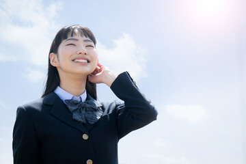 屋上の青空の中見上げる女子高校生 合格や未来を見つめるイメージ　