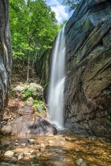 Fototapeta na wymiar Vertical long exposure shot of a small waterfall in a park