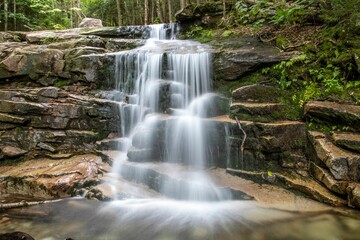 Breathtaking view of foamy waterfall flowing through rocks in the forest, long exposure
