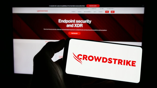 Stuttgart, Germany - 03-31-2023: Person holding smartphone with logo of cybersecurity company CrowdStrike Holdings Inc. on screen in front of website. Focus on phone display.