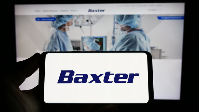 Stuttgart, Germany - 03-31-2023: Person holding smartphone with logo of US healthcare company Baxter International Inc. on screen in front of website. Focus on phone display.