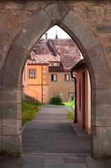 View through an archway to a house with old architecture