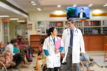 Indian male doctor discussing with assistance doctor at hospital.