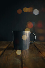 Obraz premium Black coffee mug on old wood table with black background and bokeh