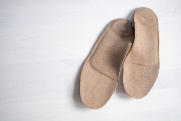 orthopedic insoles for shoes brown, made of natural materials, lies on a light surface of the table. Prevention and treatment of flat feet, shoe accessories