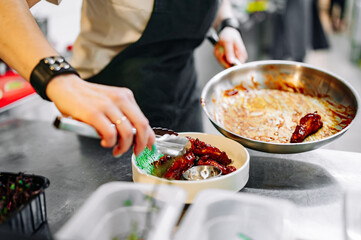 woman chef cooking chicken wings in a sauce in the kitchen