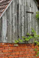 Vertical shot of an old rural stone building with a wooden rooftop