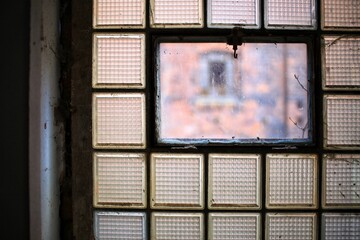 Close-up of a desolate and dirty factory window made of glass bricks