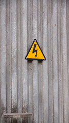 Señal de peligro por electricidad en puerta gris