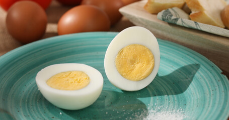 Halves of an egg on a plate. Boiled chicken eggs with bread and tomatoes. fresh eggs on the table. farm product closeup. natural healthy food. breakfast ingredients. rustic still life on a sunny day.