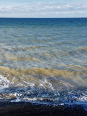 Different shades of blue on a wavy coast