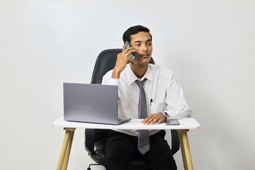 Young businessman on the phone and working in the office with a laptop on a white background
