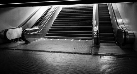 Grayscale of a staircase with escalators on the sides