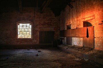 Creepy interior of abandoned factory with evening sunlight coming through brick glass window
