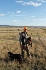 Side view of hunter carrying dead pheasant while walking on field