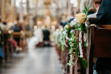 Flowers hanging on the desks of church while people are sitting in a wedding event