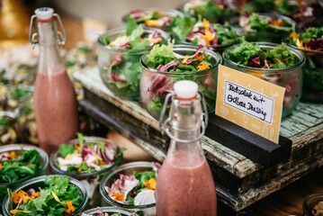 Glass bottles of sauce and many of green salad in glass bowls