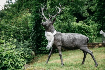 Deer sculpture with white ribbon around its neck in a garden