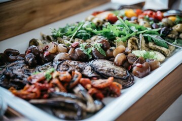 Closeup of salad with vegetables in the white plate on the wooden, blurred background