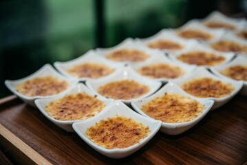 Closeup of sweet desserts in white bowls lined up on the wooden table