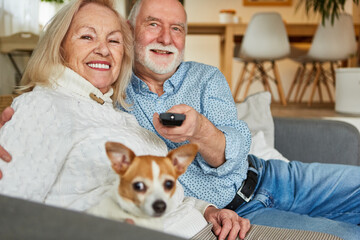 Senior couple with dog and remote control at home