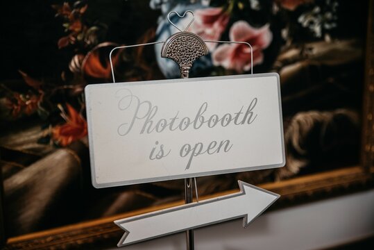 Closeup of a sign photobooth in white design with picture on the wall blurred background