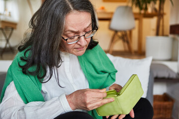 Woman as a pensioner looks into her empty wallet