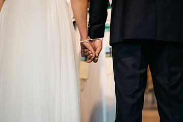 Fototapeta na wymiar Closeup of the bridegroom holding bride's hand while standing next to her