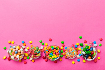different colored round candy in bowl and jars. Top view of large variety sweets and candies with copy space