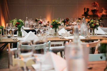 Selective focus of the glass cups, bottles and flower decorations on the tables at a wedding party