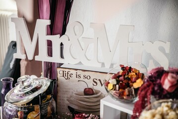 Closeup shot of the wooden Mr & Mrs sign with candy jars on the table with blur background