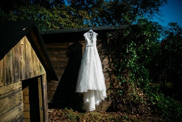 Bridal dress hanging on a wooden cottage in the garden on a sunny day