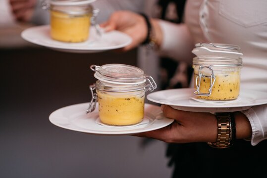 Selective focus shot of a waitress holding plate with desserts in jars