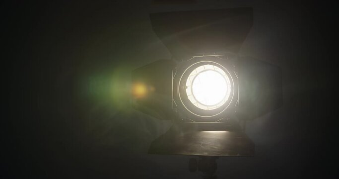 close up view of professional light source yellow color for filming, sunlight in dark room with smoke around. professional fresnel lens is mounted on video light.