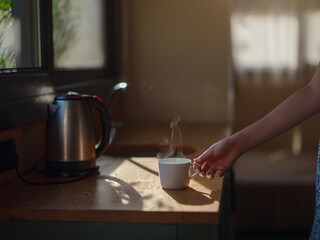Woman is drinking coffee , morning routine. Tiny house. First property. Small apartment interior design. Minimalism. Moving in. Living alone. Charming trailer house with the morning sun
