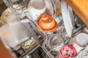 Nahaufnahme einer voll eingeräumten vollen bestückten Spülmaschine in einer Küche mit Geschirr...