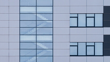 Modern building facade with staircase behind a transparent glass wall.