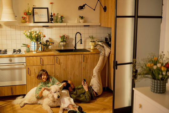 Young couple sit relaxed together with a cute dog on kitchen at home. Home coziness and domestic lifestyle concept