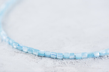 Beads or choker made of blue mother-of-pearl beads on a light background.