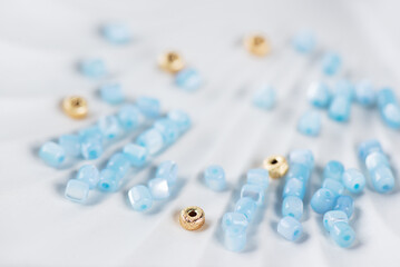 Blue mother-of-pearl and gold beads on a tray, jewelry making.
