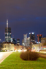 Widok nocą na centrum Warszawy od strony Mokotowa z poziomu drogi z widocznym najwyższym budynkiem w mieście i UE