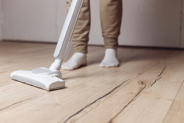 Woman Cleaning Wooden Floor With Wireless Vacuum Cleaner