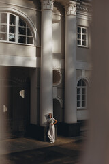 Newlywed woman in white clothing standing near white building on wedding day 