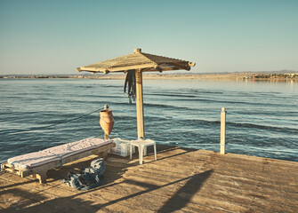 Sea diving platform with sun umbrella, bed and diving weights, color toning applied,  Egypt.