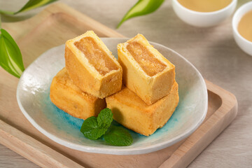 Delicious pineapple cake pastry in a plate on wooden table background with tea.