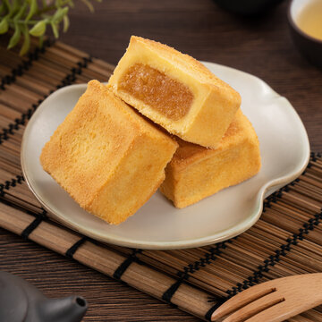 Delicious pineapple cake pastry in a plate on wooden table background with tea.