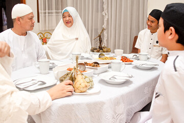 Family interaction, talking to each other while enjoying special food at dining room during eid mubarak moment.