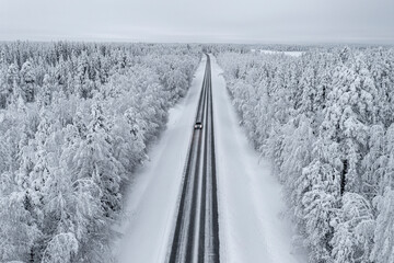 Overhead view of car driving on slippery empty road in the snowy forest, Lapland, Finland